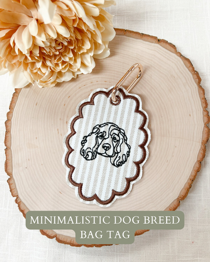 Minimalistic dog breed bag tag on a wooden surface with a flower.